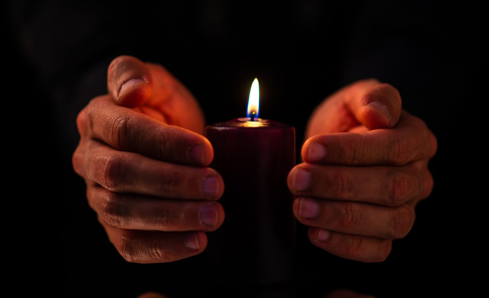 Front view of dark candle with male on a dark surface