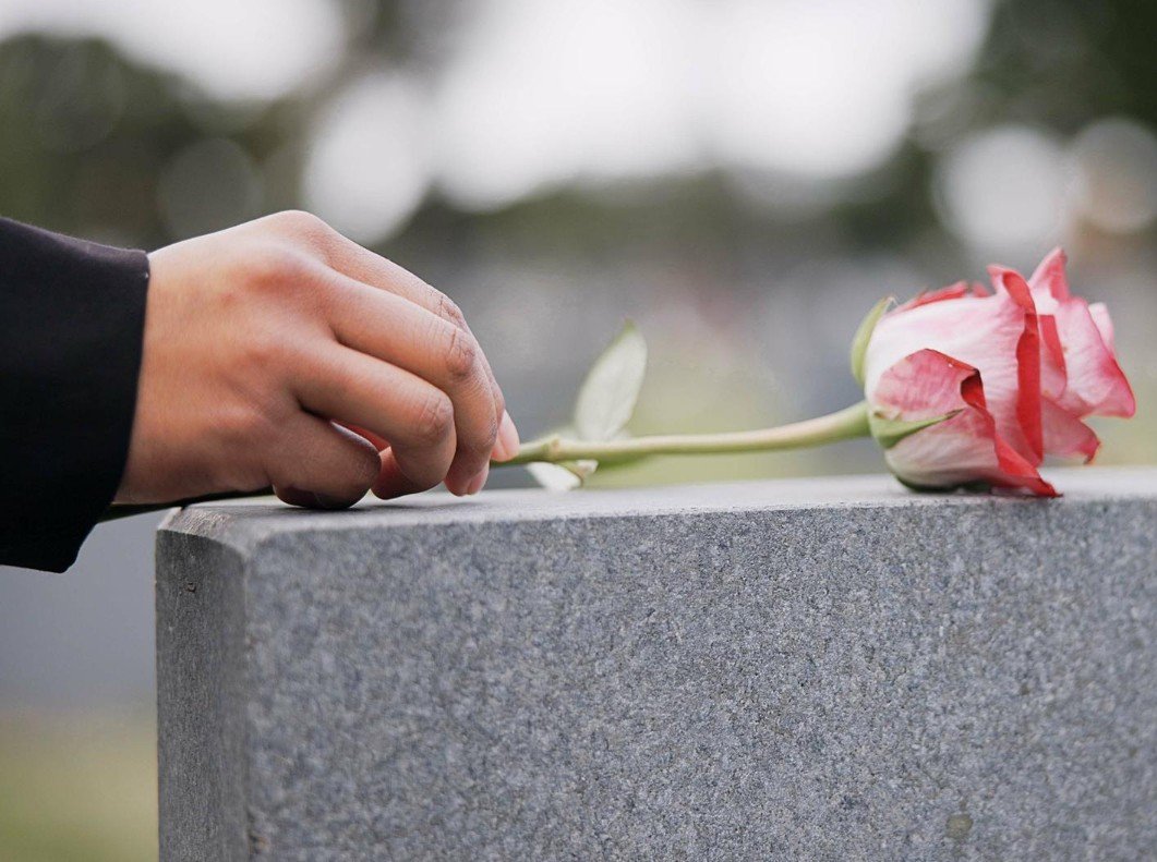 Funeral cemetery and hands with rose on tombstone for remembrance ceremony