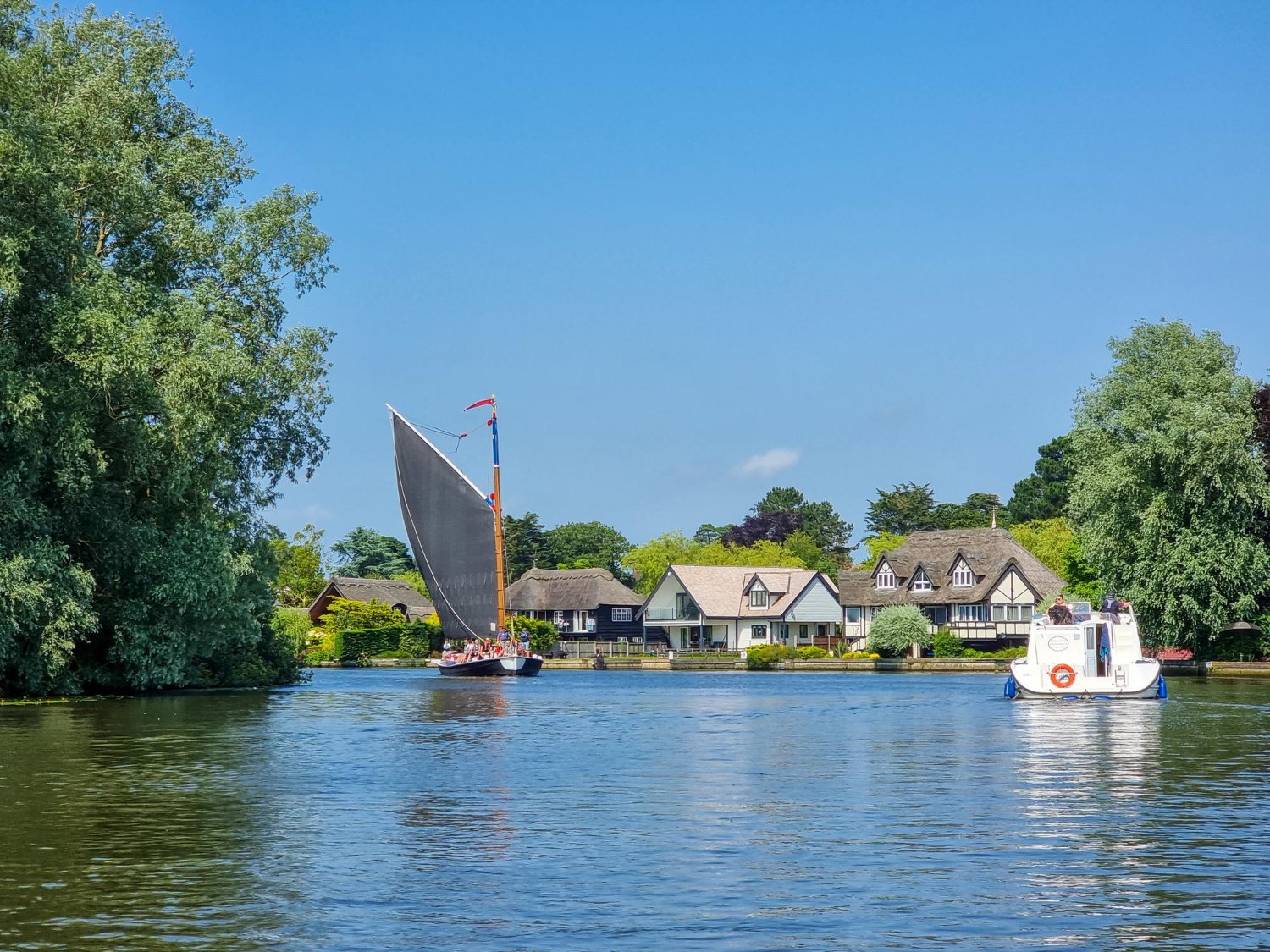 Traditional norfolk wherry sailboat and holiday boats on the broads england