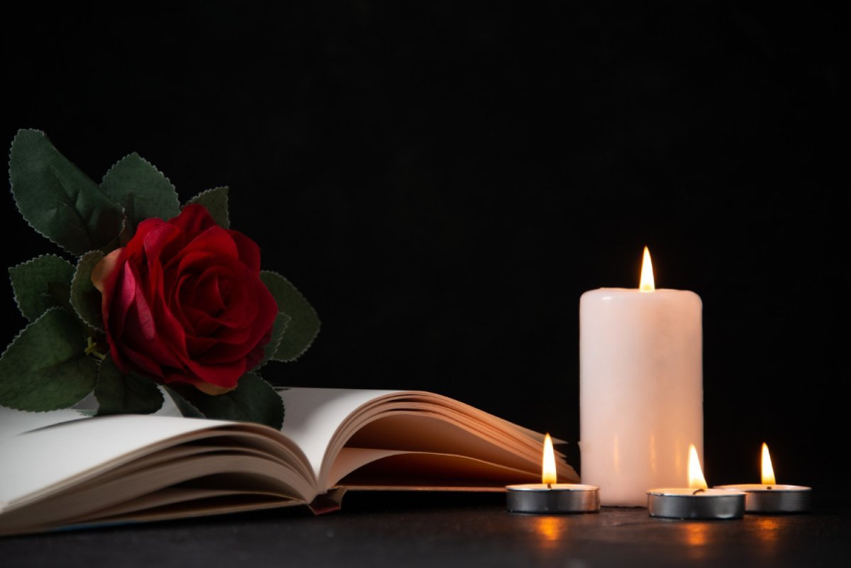 burning-candles-with-open-book-red-flower-dark-surface